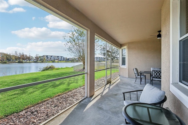 sunroom featuring ceiling fan and a water view