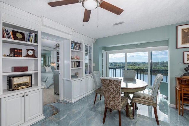 dining space featuring a textured ceiling, built in features, and a water view