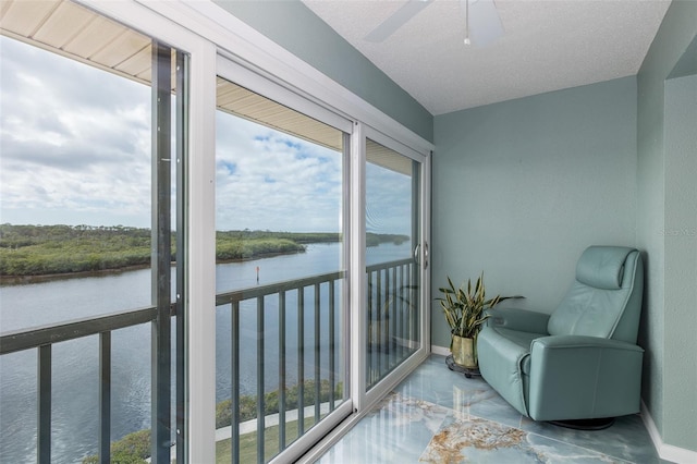 sunroom featuring ceiling fan and a water view