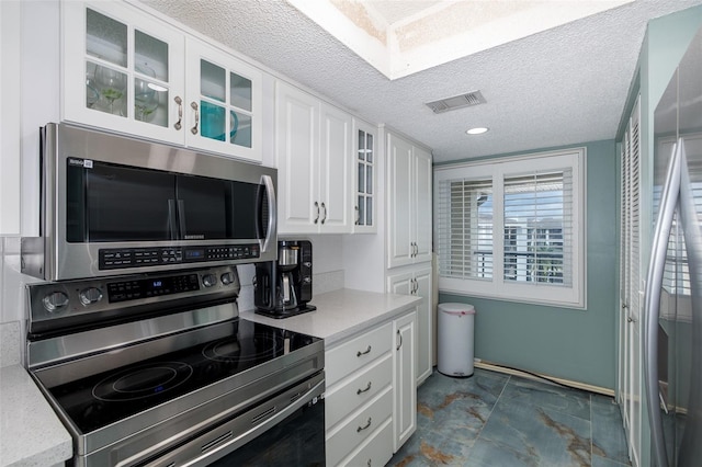 kitchen featuring a textured ceiling, stainless steel appliances, and white cabinetry