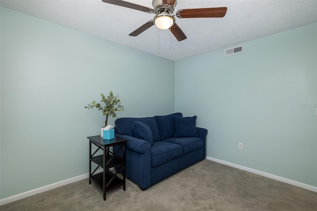 sitting room with ceiling fan, carpet, and a textured ceiling