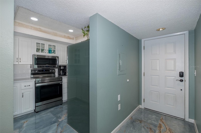 kitchen featuring appliances with stainless steel finishes, white cabinets, and a textured ceiling