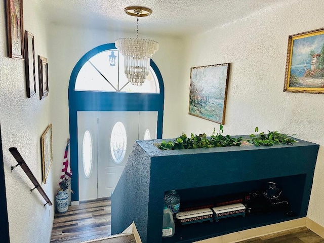 entrance foyer with hardwood / wood-style floors, a textured ceiling, and a chandelier