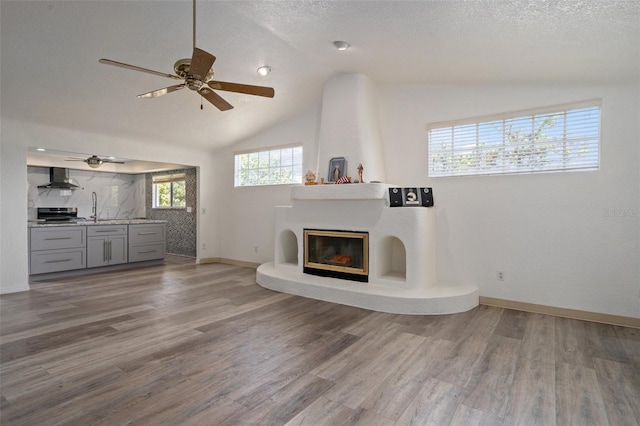 unfurnished living room featuring ceiling fan, wood-type flooring, and vaulted ceiling