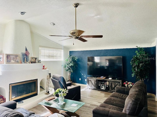 living room featuring a fireplace, hardwood / wood-style floors, a textured ceiling, and vaulted ceiling