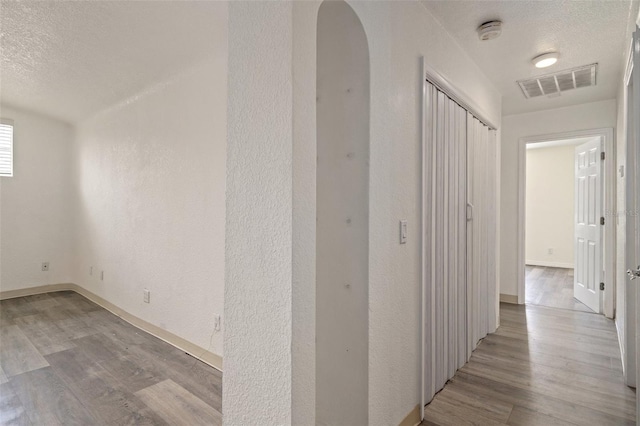 hallway with a textured ceiling and light hardwood / wood-style floors