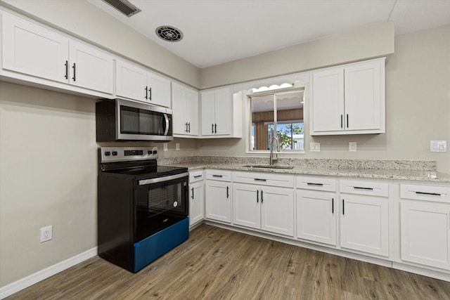 106 Aurora St E, Venice, FL 34285 - kitchen with white cabinets, stainless steel microwave, a sink, and black electric range oven