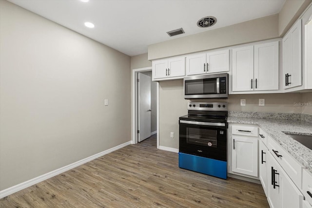 106 Aurora St E, Venice, FL 34285 - kitchen with range with electric stovetop, visible vents, baseboards, stainless steel microwave, and light wood-style flooring