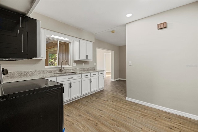 106 Aurora St E, Venice, FL 34285 - kitchen featuring white cabinets, baseboards, black electric range oven, and a sink