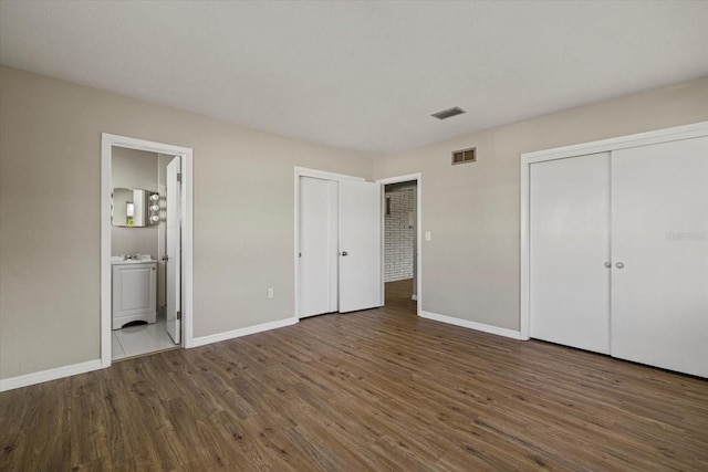 106 Aurora St E, Venice, FL 34285 - unfurnished bedroom featuring connected bathroom, multiple closets, baseboards, wood finished floors, and visible vents