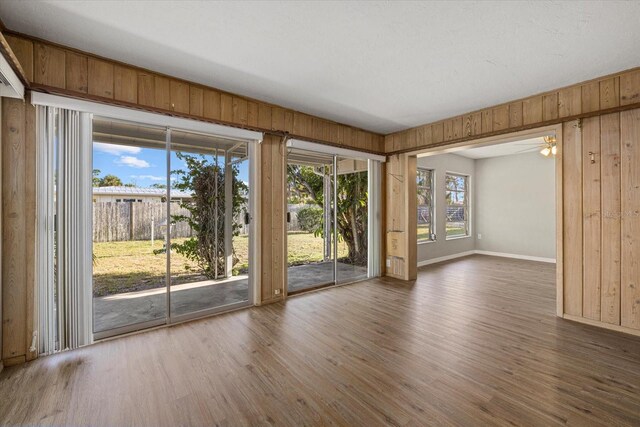 106 Aurora St E, Venice, FL 34285 - empty room featuring a ceiling fan, baseboards, wood walls, and wood finished floors