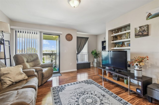 living room featuring built in shelves and wood-type flooring