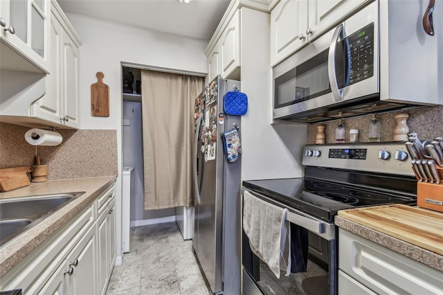 kitchen featuring wood counters, tasteful backsplash, stainless steel appliances, sink, and white cabinetry