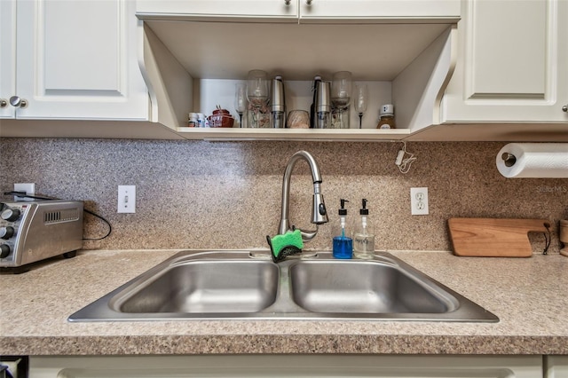 kitchen featuring tasteful backsplash, white cabinetry, and sink