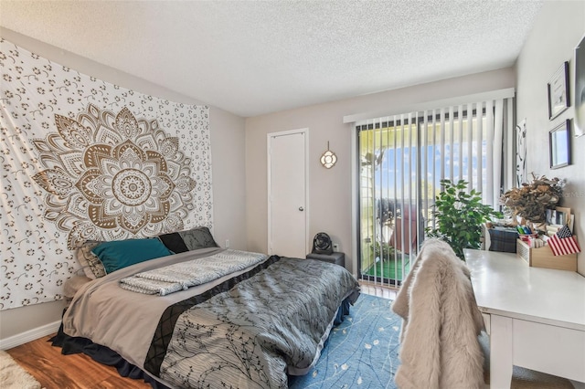 bedroom featuring hardwood / wood-style floors, a textured ceiling, and access to outside