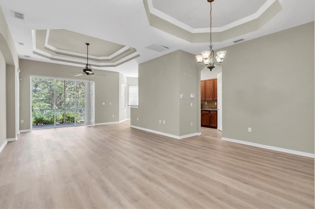 unfurnished room with a raised ceiling, crown molding, ceiling fan with notable chandelier, and light wood-type flooring