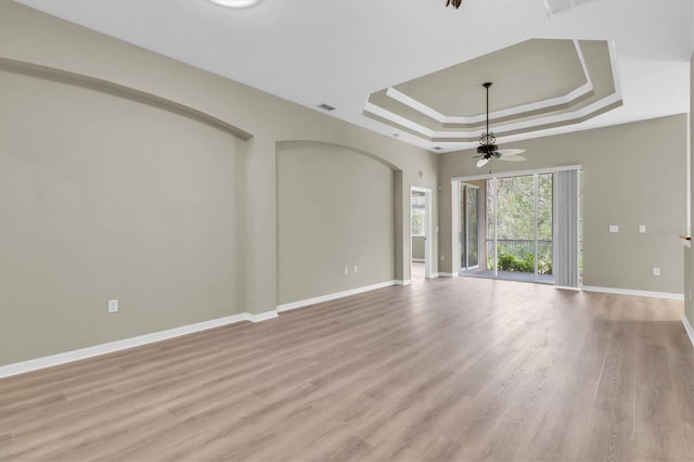 unfurnished living room with a tray ceiling, ceiling fan, and light wood-type flooring