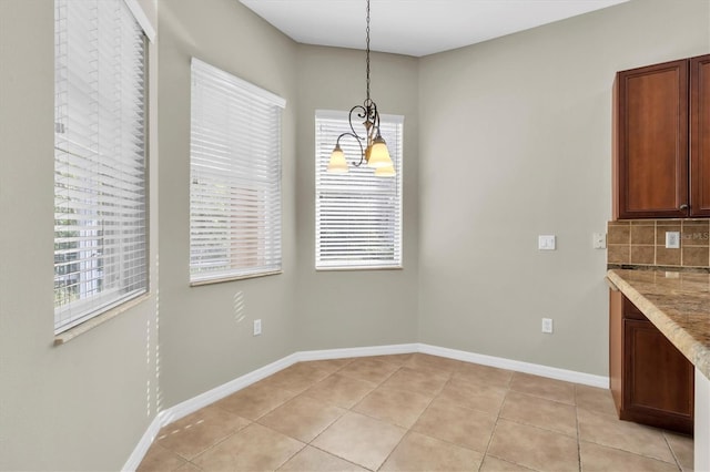 unfurnished dining area with light tile patterned floors and a chandelier