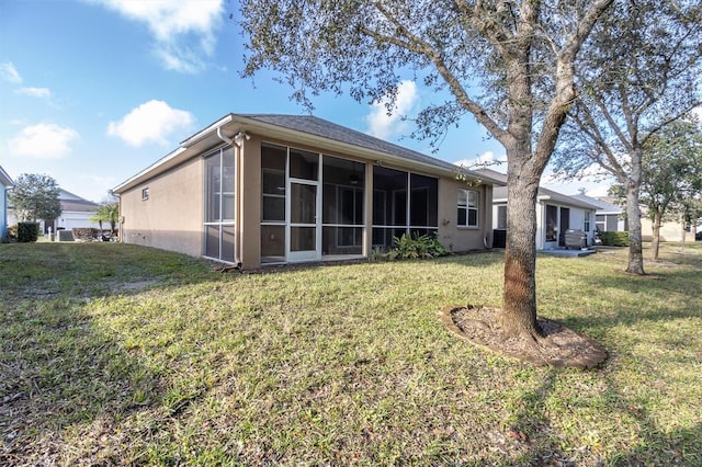 back of property with a yard and a sunroom