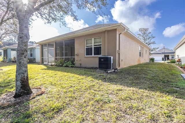 back of property with central AC unit, a sunroom, and a lawn