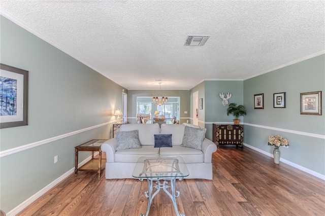 living room featuring crown molding, hardwood / wood-style floors, a textured ceiling, and a notable chandelier