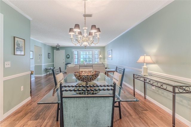 dining space with crown molding, hardwood / wood-style floors, and a notable chandelier