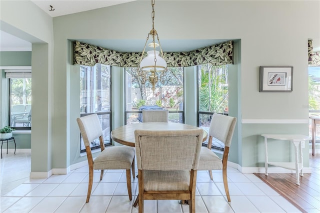 tiled dining room featuring vaulted ceiling