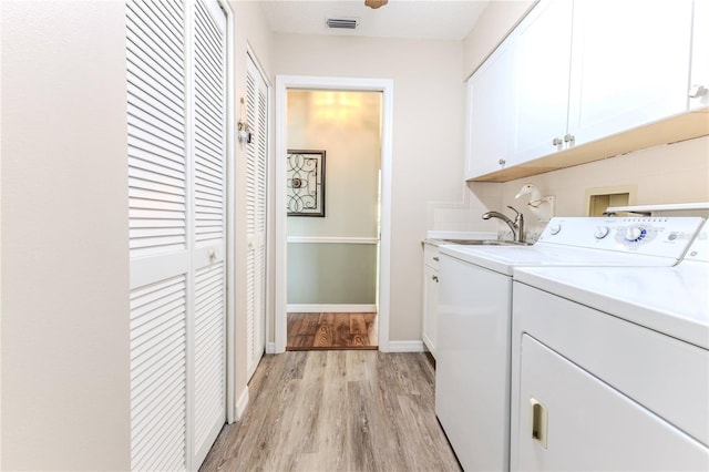 clothes washing area featuring cabinets, sink, light hardwood / wood-style floors, and washing machine and clothes dryer