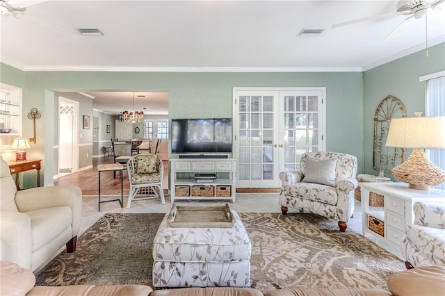 living room featuring crown molding, french doors, light tile patterned floors, and ceiling fan with notable chandelier