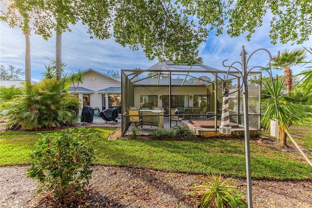 rear view of house featuring glass enclosure, a yard, and a patio