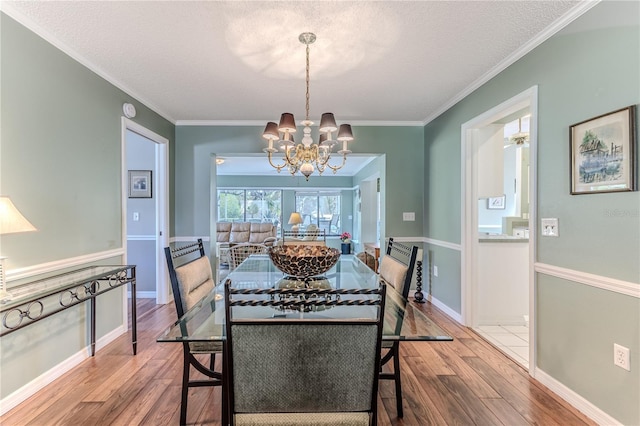 dining space featuring a chandelier, a textured ceiling, hardwood / wood-style flooring, and crown molding