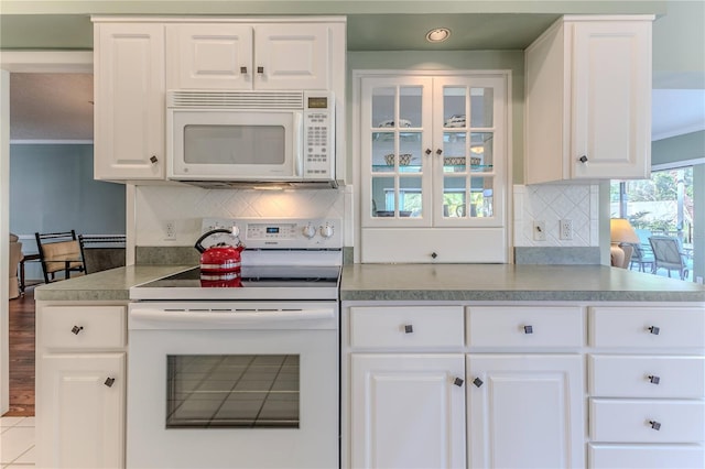 kitchen with white cabinets, light tile patterned floors, white appliances, and decorative backsplash