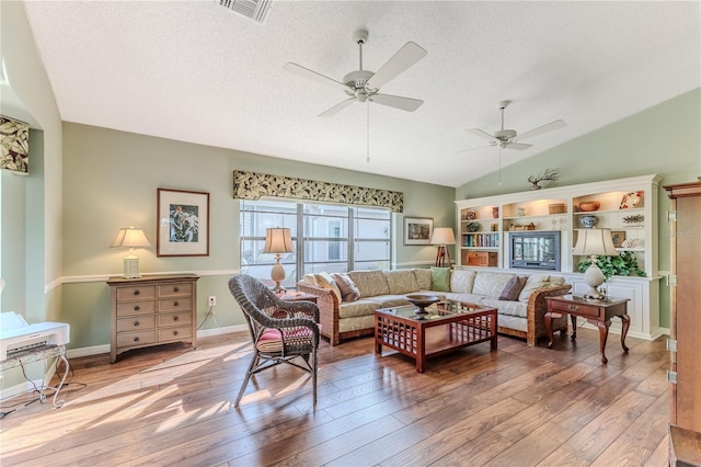 living room featuring a textured ceiling, hardwood / wood-style flooring, ceiling fan, and lofted ceiling