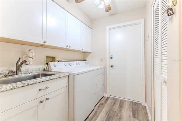 laundry room with washer and clothes dryer, light hardwood / wood-style flooring, cabinets, and sink