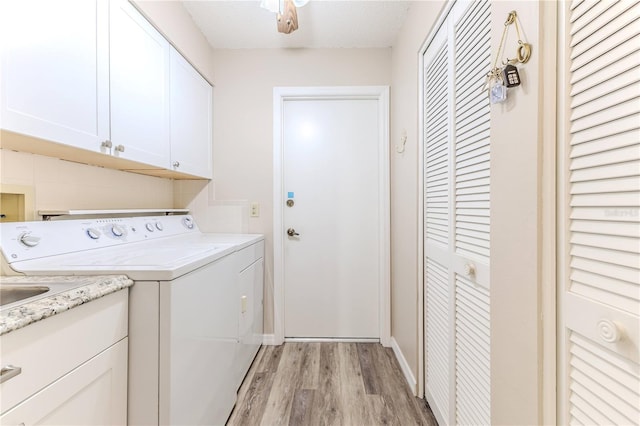 washroom with washing machine and clothes dryer, light hardwood / wood-style flooring, cabinets, and a textured ceiling