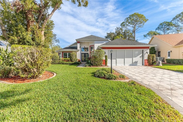 view of front of property with central AC unit, a garage, and a front lawn