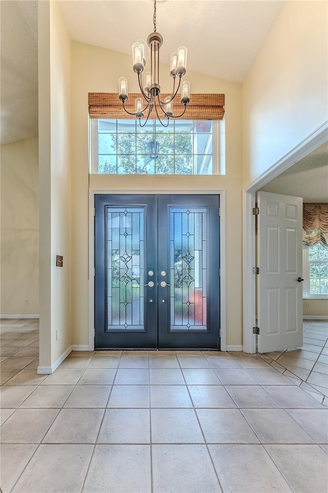 tiled entrance foyer featuring french doors, high vaulted ceiling, and a notable chandelier