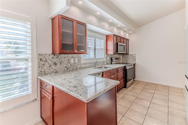 kitchen with backsplash, sink, light tile patterned floors, light stone counters, and stainless steel appliances