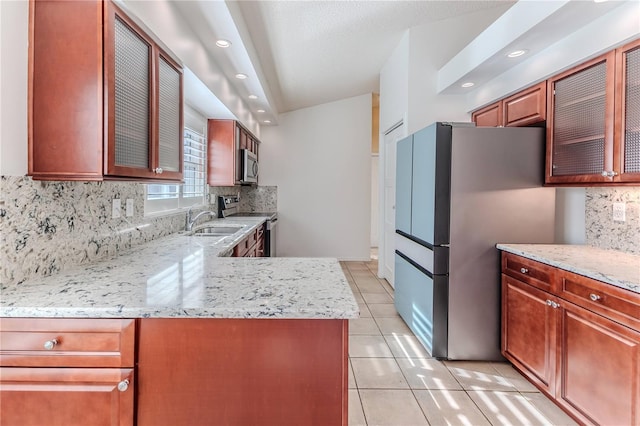 kitchen featuring tasteful backsplash, light stone countertops, light tile patterned flooring, and appliances with stainless steel finishes