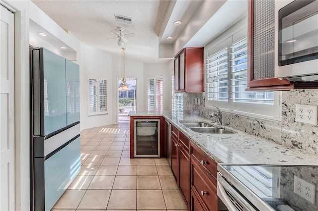 kitchen with sink, tasteful backsplash, high end refrigerator, pendant lighting, and range