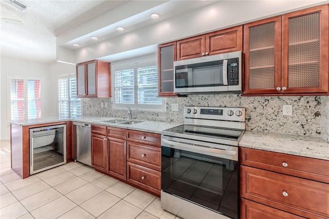 kitchen featuring sink, light tile patterned floors, appliances with stainless steel finishes, tasteful backsplash, and light stone counters