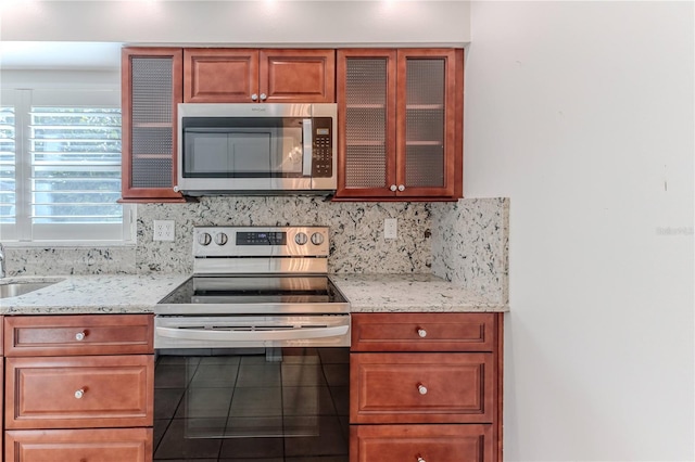 kitchen with backsplash, light stone countertops, sink, and stainless steel appliances