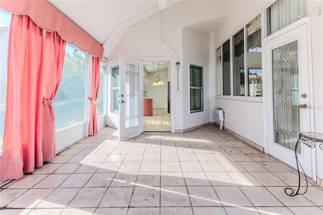 unfurnished sunroom with a chandelier, a wall unit AC, and french doors