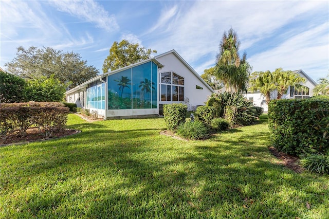 rear view of house with a sunroom and a yard