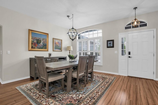 dining space with wood-type flooring and a notable chandelier