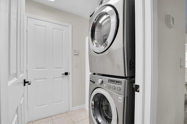 laundry area with stacked washer / dryer and light tile patterned flooring