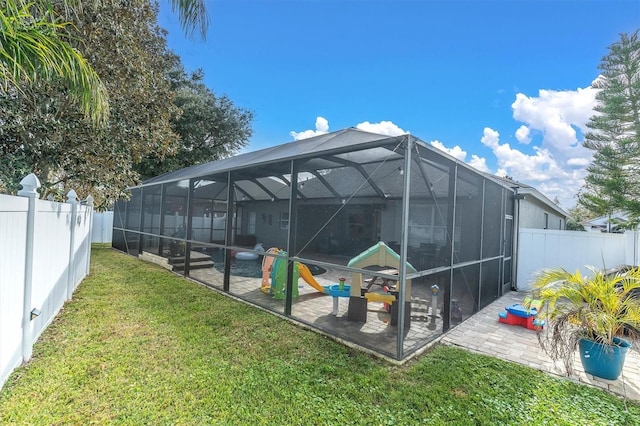 rear view of property featuring a lawn, glass enclosure, and a playground