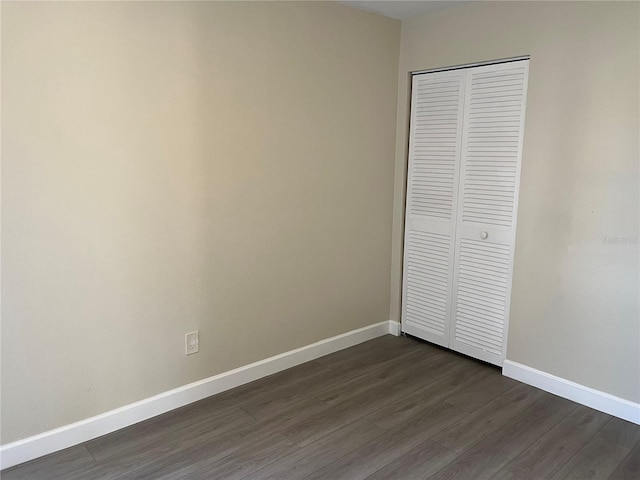 unfurnished bedroom with a closet and dark hardwood / wood-style floors