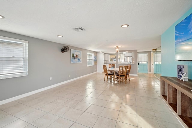 dining area featuring light tile patterned floors, a healthy amount of sunlight, and a textured ceiling