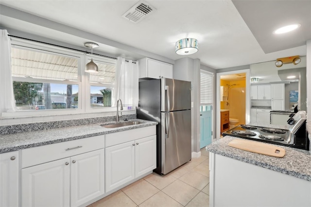 kitchen with decorative light fixtures, white cabinetry, stainless steel refrigerator, and sink